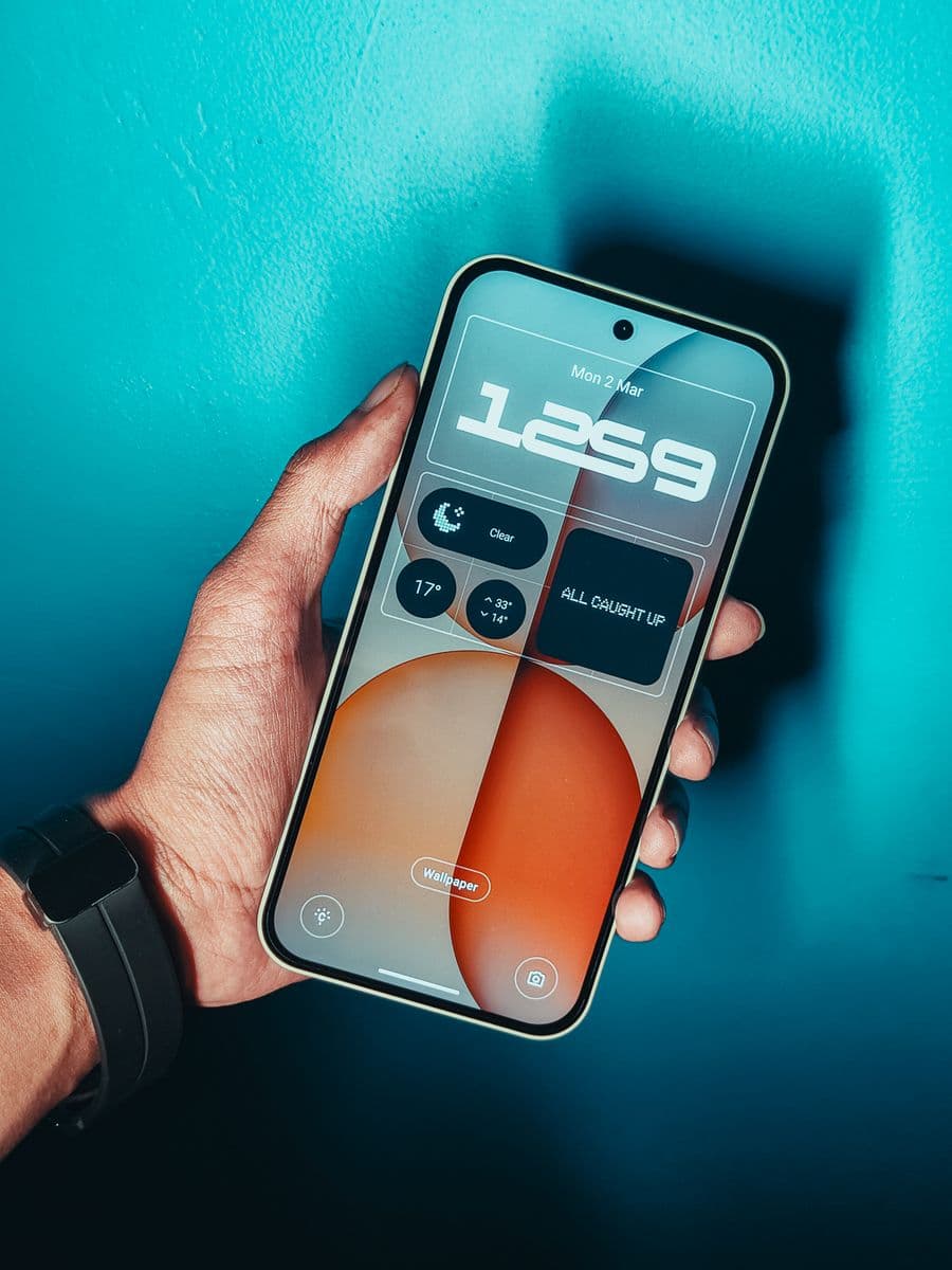 Une main tient un smartphone affichant une interface avec des widgets.